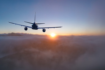 Flying of the passenger plane above the clouds and mountains.