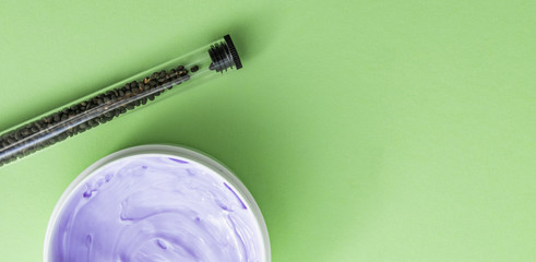 Babchi seeds in glass tube and purple skin cream in white jar, bakuchiol ingredient.