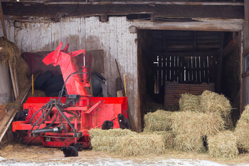 Family of black cats lounging on red farm machine and bales of hay in an open barn in winter in the rural part of Saint-Augustin-de-Desmaures near Quebec City, Quebec, Canada © Anne Richard