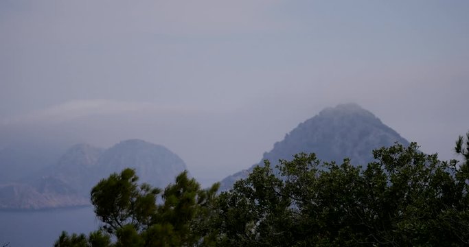 View to an unhabited islands through the trees in Gelidonya cape in Mediterranean sea, Antalya, Turkey. Windy weather.