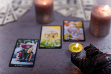 Divination cards alignment with black Buddha statue, money banknotes and candles. Mystery,...