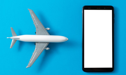 Toy airplane and smartphone mock up on blue background, flight and travel concept.