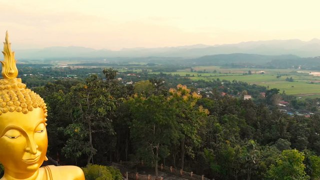 Thailand Wat Jom Thong Golden buddha statue aerial footage view during sunset, slowly fly backward.