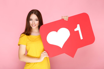Young woman holding paper card with heart and number one on pink background