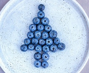 Alternative Christmas tree made of blueberries at the concrete background.  