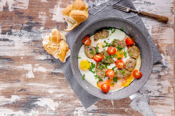 Fried eggs with vegetable nuggets in a gray ceramic frying pan. Tasty breakfast. Copy space