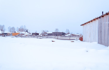 winter village  in the snow on a sunny day. street of wooden houses  road at houses near the forest, no people. Siberian.