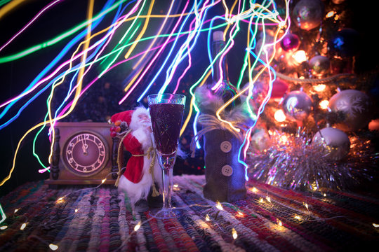 Red wine in crystal glass with bottle on colorful carpet with creative New Year artwork decorations. Copy space