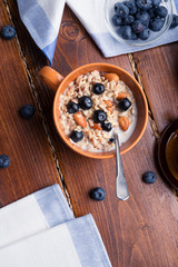 bowl of oatmeal porridge with blueberries, fruits,  almonds and coconut milk. Healthy and tasty vegan breakfast. top view, flat lay.