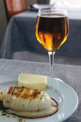 Grilled cuttlefish with sauce on a white plate. Delicious wholesome dinner at a Spanish fish restaurant. A gastronomic trip to Valencia. Vertical orientation.