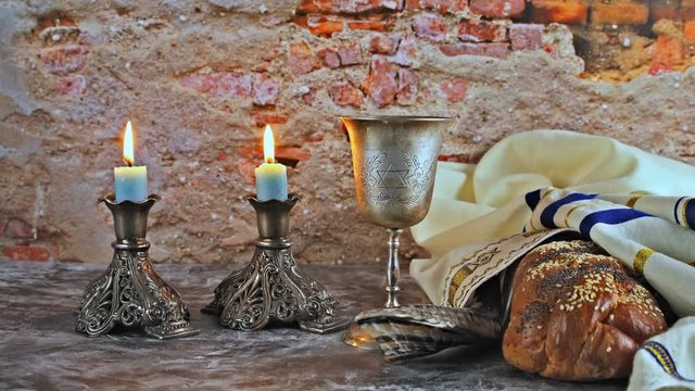 Shabbat Jewish holiday with challah bread on a candles and cup of wine.
