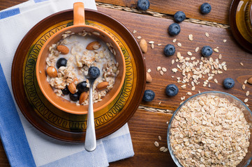 Fototapeta na wymiar bowl of oatmeal porridge with blueberries, fruits, almonds and coconut milk. Healthy and tasty vegan breakfast. top view, flat lay.