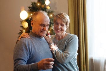 happy Senior couple with Sparklers at home at Christmas time. New Year, Christmas, holiday concept.