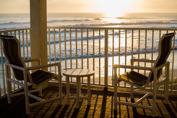 Two deck chairs and a small table in the balcony with a view to the beautiful sunset over the sea