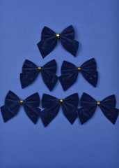 Christmas tree of blue bows on a blue background. 2020 trend. Color of the year.