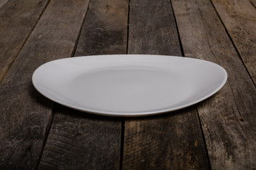 Top view of blank white dish and white tablecloth on a wood background with copy space