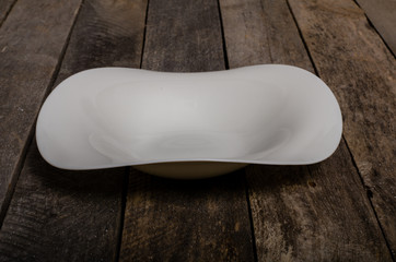 Top view of blank white dish and white tablecloth on a wood background with copy space