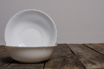 Top view of blank white dish and white tablecloth on a wood background with copy space