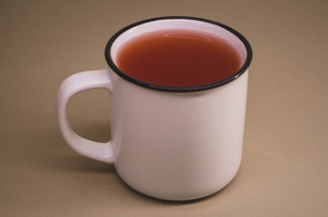 white mug with red tea on a dull brown background