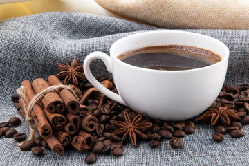 cup of black coffee on colored cloth and roasted coffee beans close up