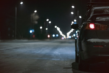 Empty night winter road and a car on roadside.