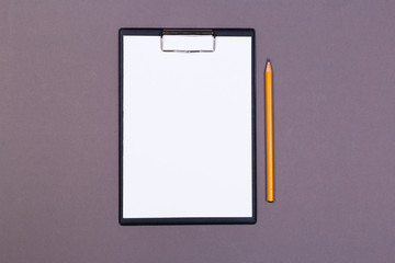 Clipboard with a white sheet and pen on a gray-dark background. View from above. space for text