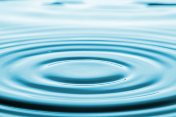 Naklejka na ściany i meble Closeup Water drop falling on the surface of the water and beautiful circular wave ripple, fresh natural mineral water drink water concept