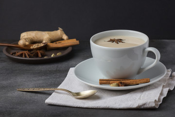 Traditional indian masala tea in a white cup on a dark background, horizontal orientation
