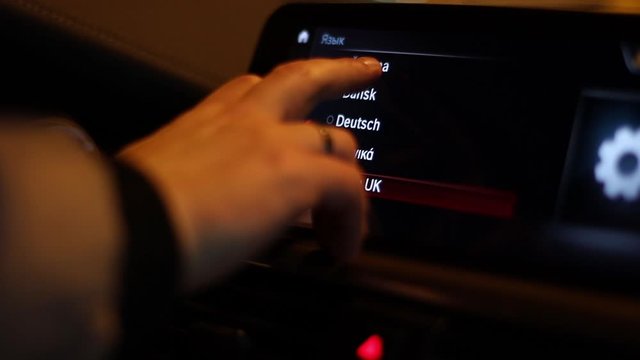 The driver selects the language of the multimedia device in the car.