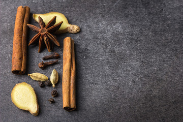 Fototapeta na wymiar various types of spices for masala tea on a dark background, top view, copy space