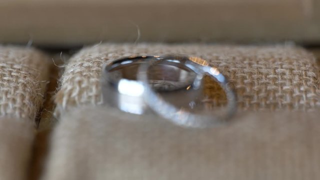 Rack focus to reveal wedding rings on brown burlap