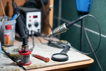 Soldering iron, tin and solder on a electrician worker workbench background.