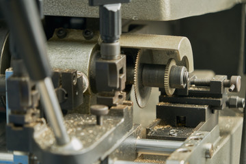 Fototapeta na wymiar Levers, belts and elements of a key cutting machine. Image of the mechanisms and of the shavings of excess metal.