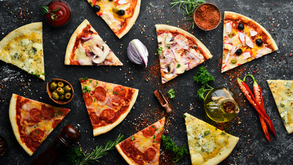 Assortment of pizza sliced on black stone background. Top view. free space for your text. Rustic style.