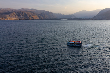 Boat sailing in Oman fjords, sea mountain landscape, Khasab. Musandam peninsula.