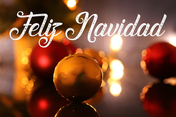 Christmas greetings with spanish text Feliz Navidad (merry christmas) and Christmas baubles