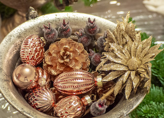 Christmas composition of gold pink balls, cone, flower and berries in bronze bowl. Christmas and New year background