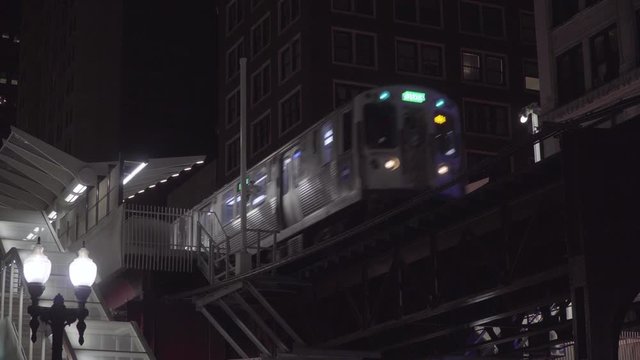 Night time exterior establishing shot of generic Chicago style apartment building over looking loop tracks as passenger train speeds through station platform outside building