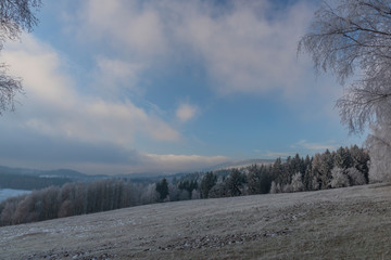White snowy meadow with Doupovske mountains in mist