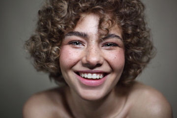 Vintage style portrait of smiling beautiful young freckled girl with curly hair, selective focus