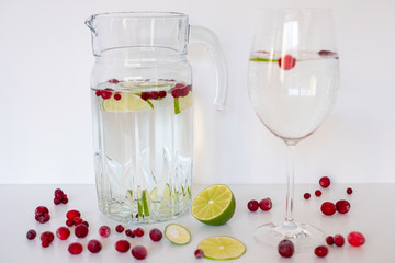 Healthy drink with water, lime, cranberries on white background