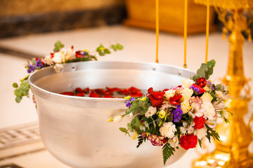 The sacrament of the rite baptism of a child in an Orthodox Christian church. Chan for ablution and altar with a bible.