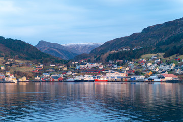 Fototapeta na wymiar fishing village with colorful wooden fishing huts in the fjords of Norway on a sunny day in spring within a beautiful landscape shot from a boat 