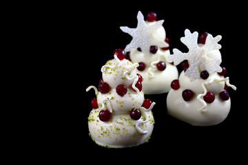 Three white christmas tree mousse desserts with cranberries and white chocolate snowflake decorations