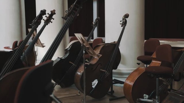 Dolly shot of few cellos on scene in a classical music style concert hall