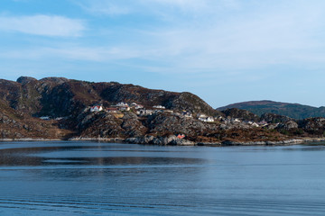 Fototapeta na wymiar fishing village with colorful wooden fishing huts in the fjords of Norway on a sunny day in spring within a beautiful landscape shot from a boat 