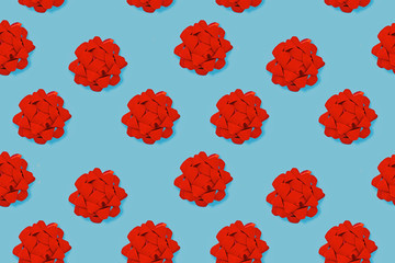 Big red gift wrapping ribbon bows on blue background arranged neatly in a row
