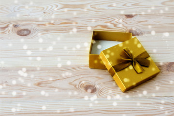 Gift box on a light wooden background. Elegant golden open gift box. The concept of Christmas and New Year holidays. Flat layout.