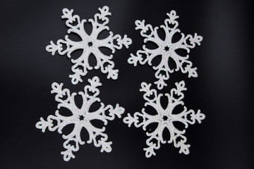 Big white snowflakes on a black background. Several white sparkling snowflakes form an abstract background for wallpaper.
