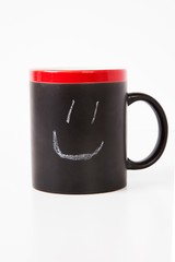Close-up of smiley drawn on cup over white background